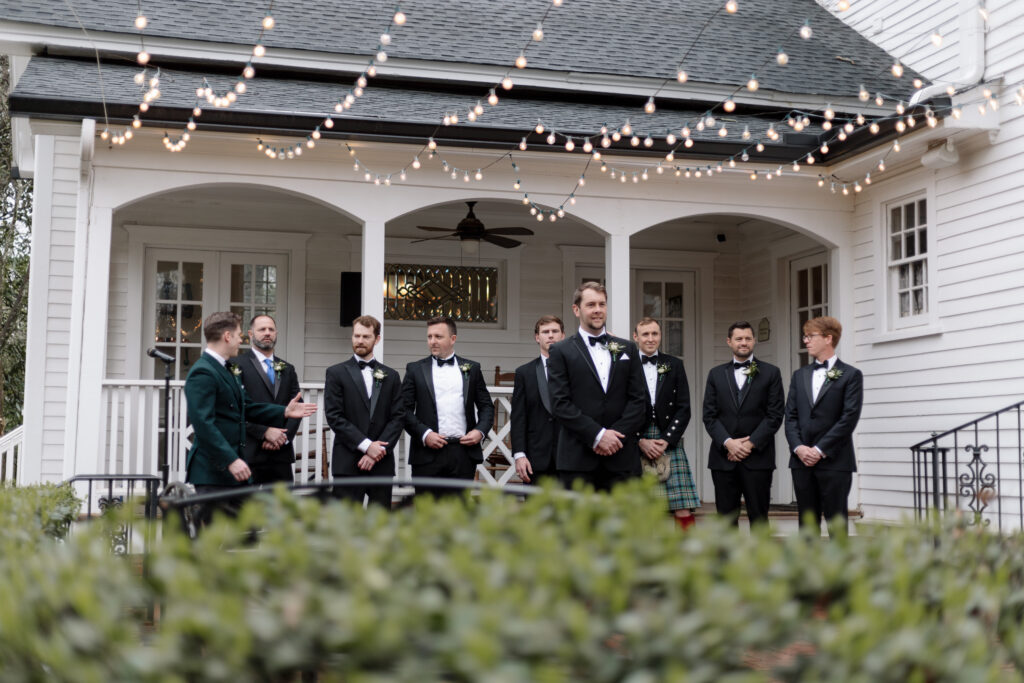 groom and groomsmen standing outside the wedding venue taking photos