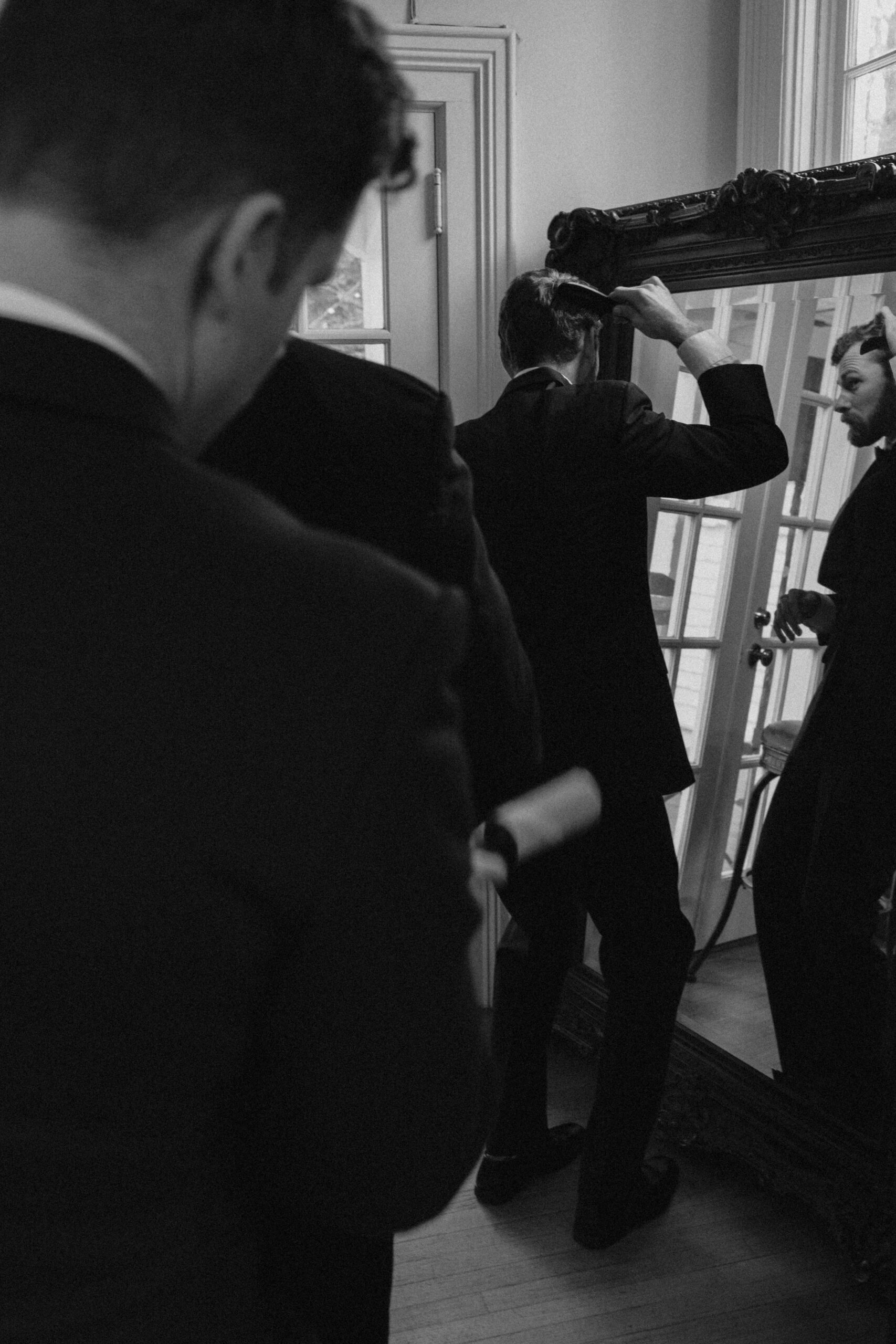 men getting ready and brushing their hair in a mirror