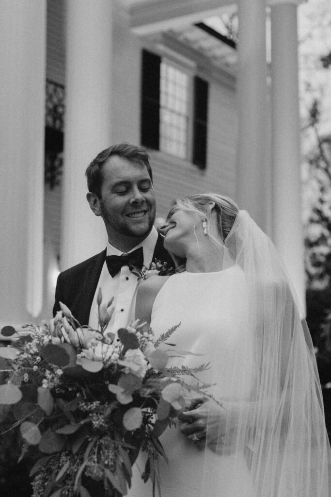 bride leaning back on her groom while holding her wedding flowers