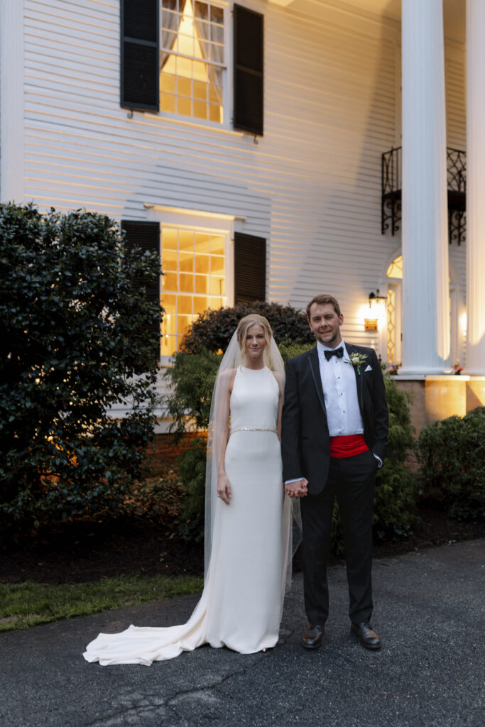 Bride and groom standing in front of their venue for wedding portraits