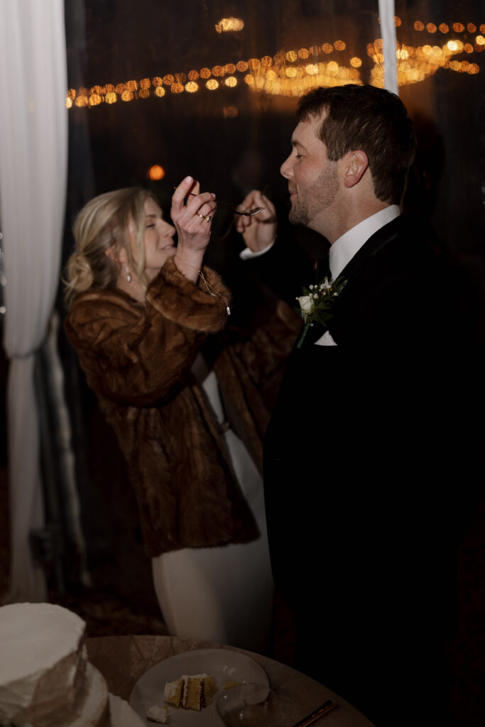 bride and groom feeding each other cake at their reception