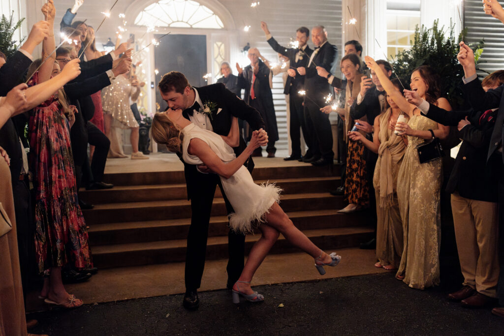 groom dip kissing his bride during his wedding exit of sparklers