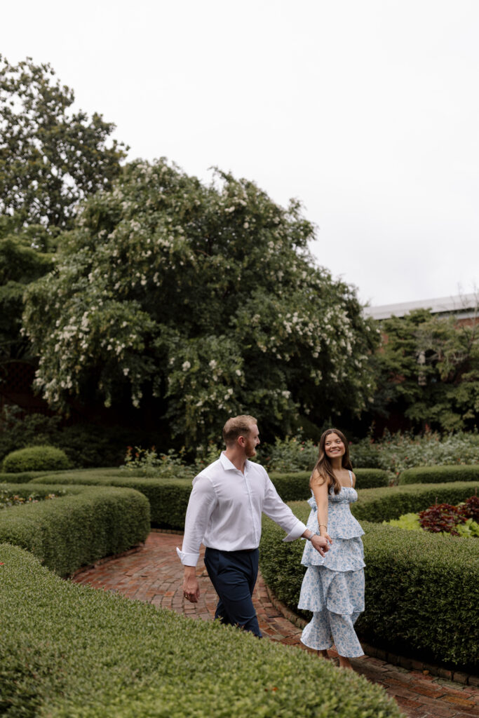 Guy and girl walk around the rose garden between the hedges