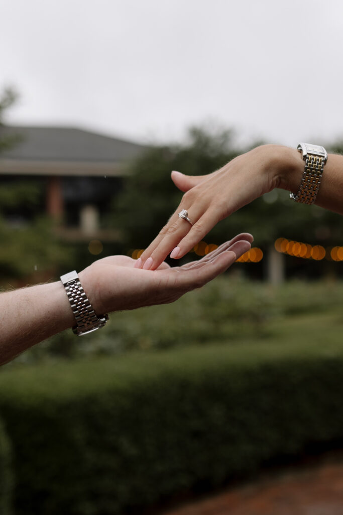 Hands grazing each other while showing off the engagement ring