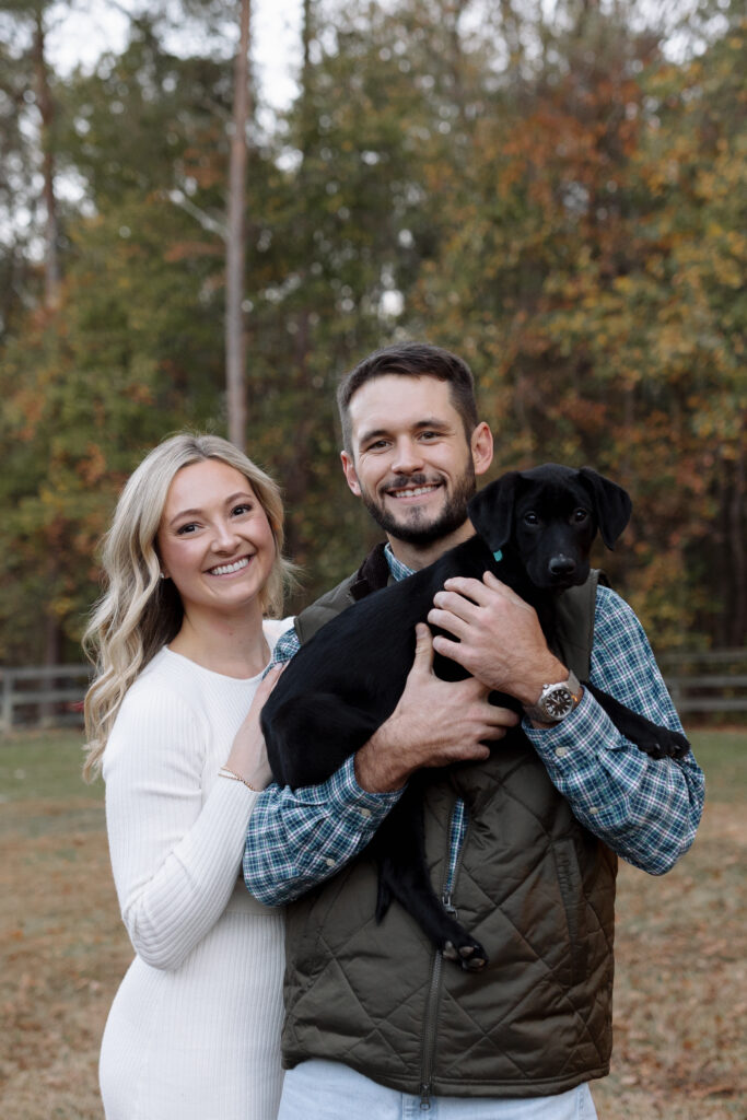 couple smiling while holding their puppy during their photo session in spartanburg