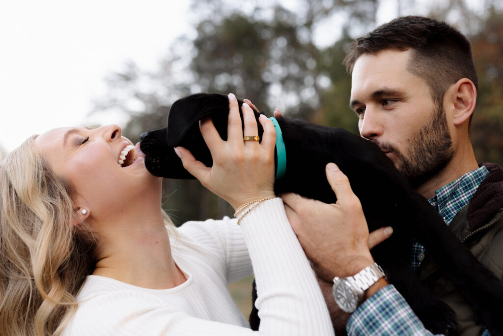 Puppy licking woman's face while dad kisses his neck