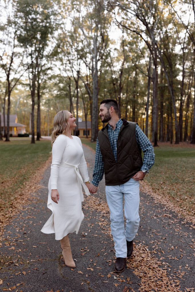 couple holding hands and smiling at each other during their engagement session in spartanburg