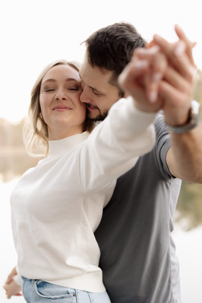 couple holding hands and dancing by the water in their engagement session