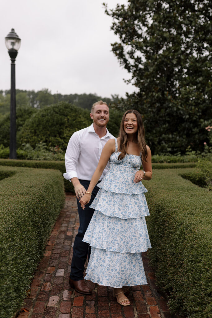 Guy and girl hold hands while laughing at the camera