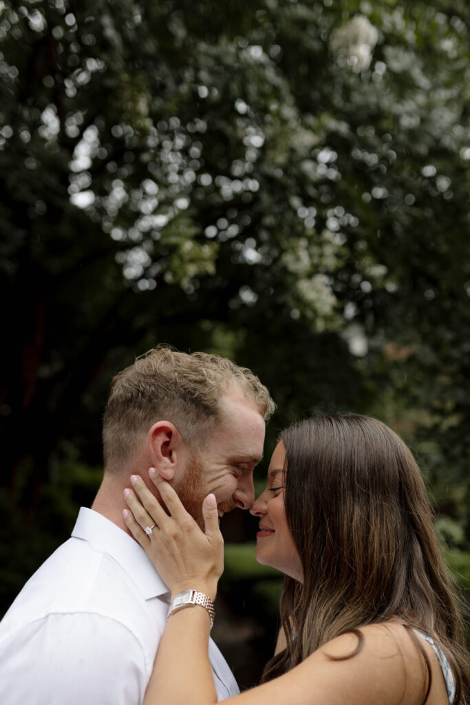 Girl holds fiance's face while they touch noses