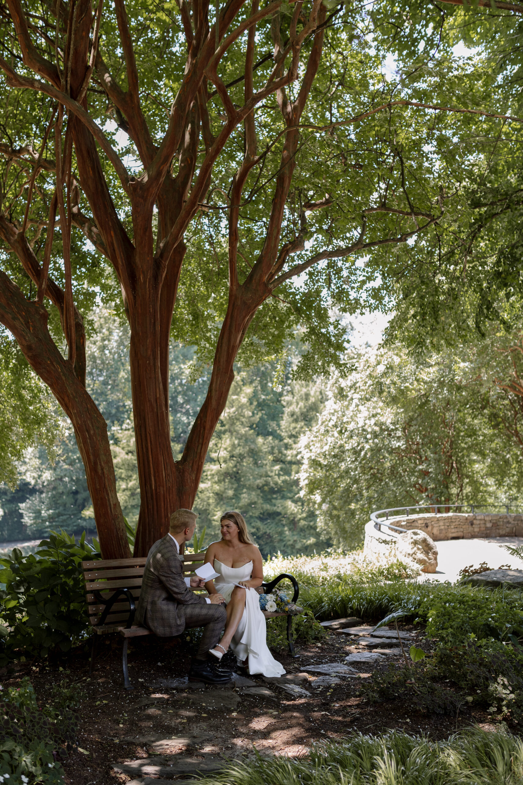 couple sitting on a bench in falls park reading their private vows to each other