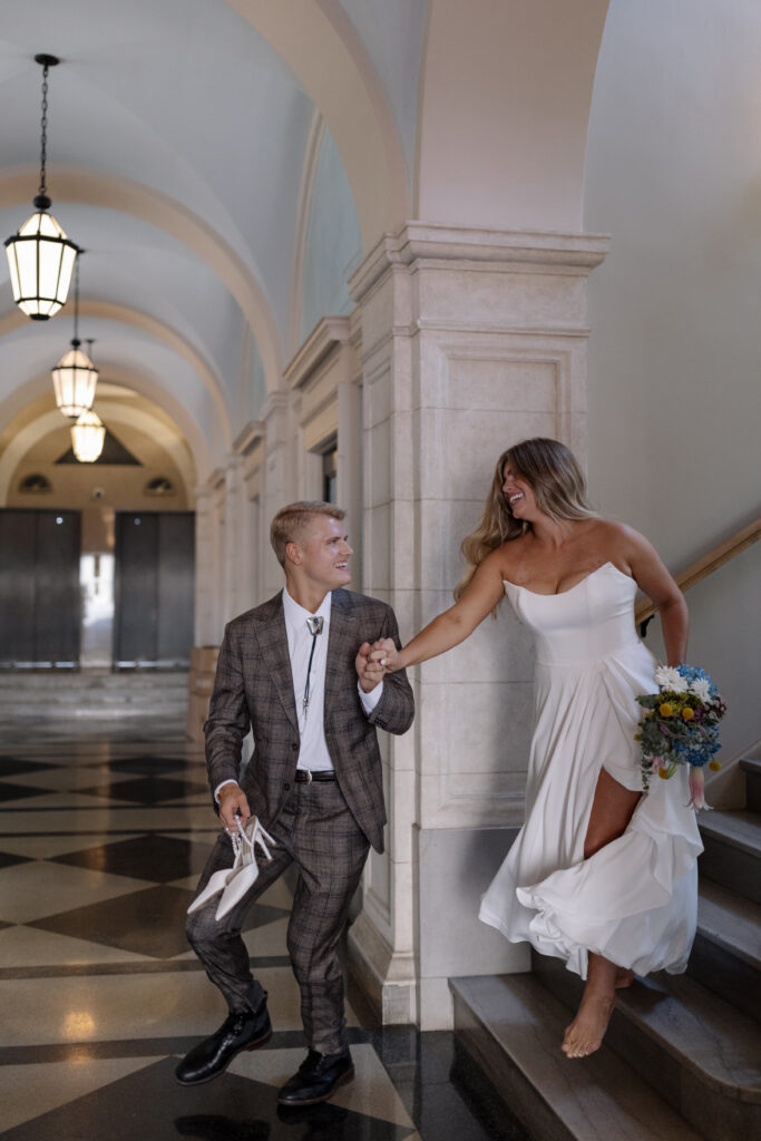 Groom leading the bride down steps while he holds her hand