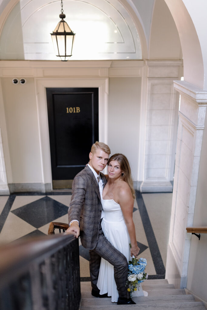 Bride and groom smiling and hugging as they look up the stairs