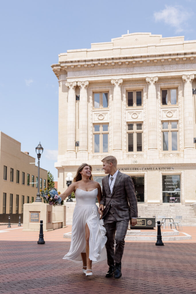 bride and groom running across the street downtown Greenville SC