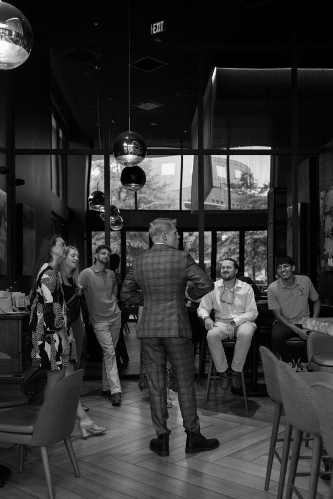 groom standing in front of his buddies while looking to the right and adjusting his suit in greenville sc