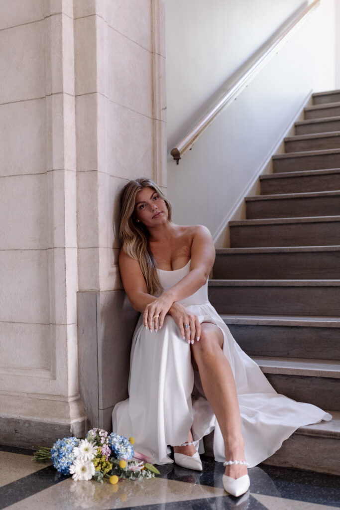 bride sitting at the bottom of the steps posing for a photo