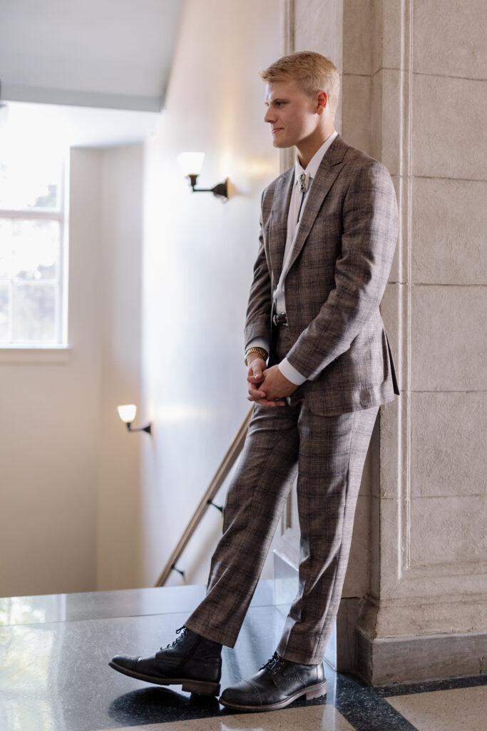 groom looking at his bride while leaning against the wall