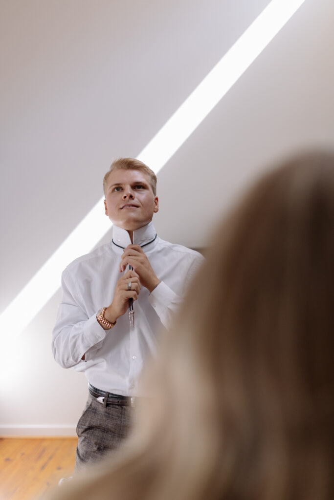 groom putting on his bolo tie in front of his bride in greenville sc for their elopement