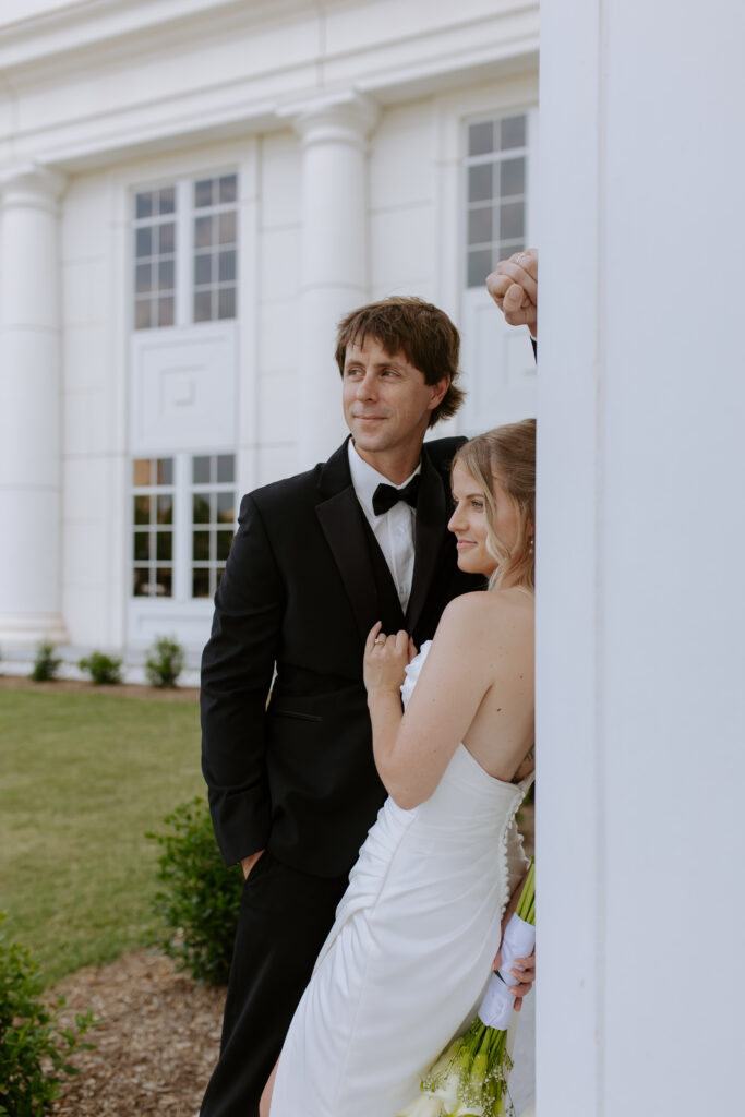 Bride and groom posing by the columns of the courthouse in spartanburg, sc. 