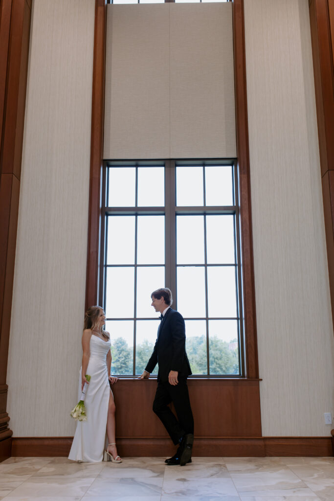 Portraits of the bride and groom by big windows of the spartanburg county courthouse. 