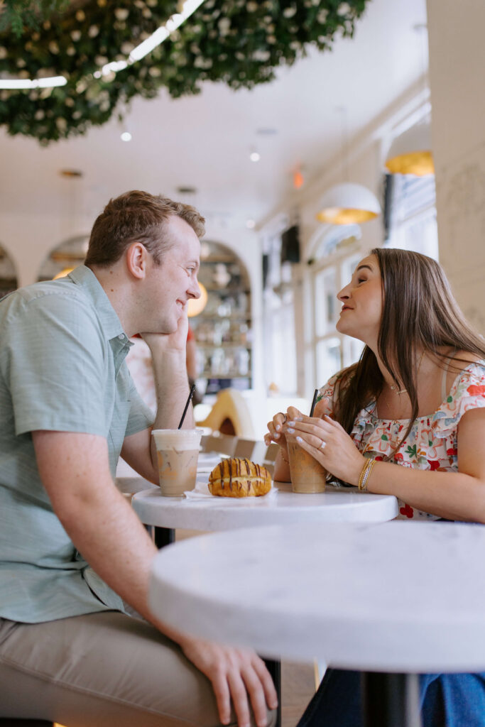 couple in greenville sc smiling at each other on a date with pastries and coffees