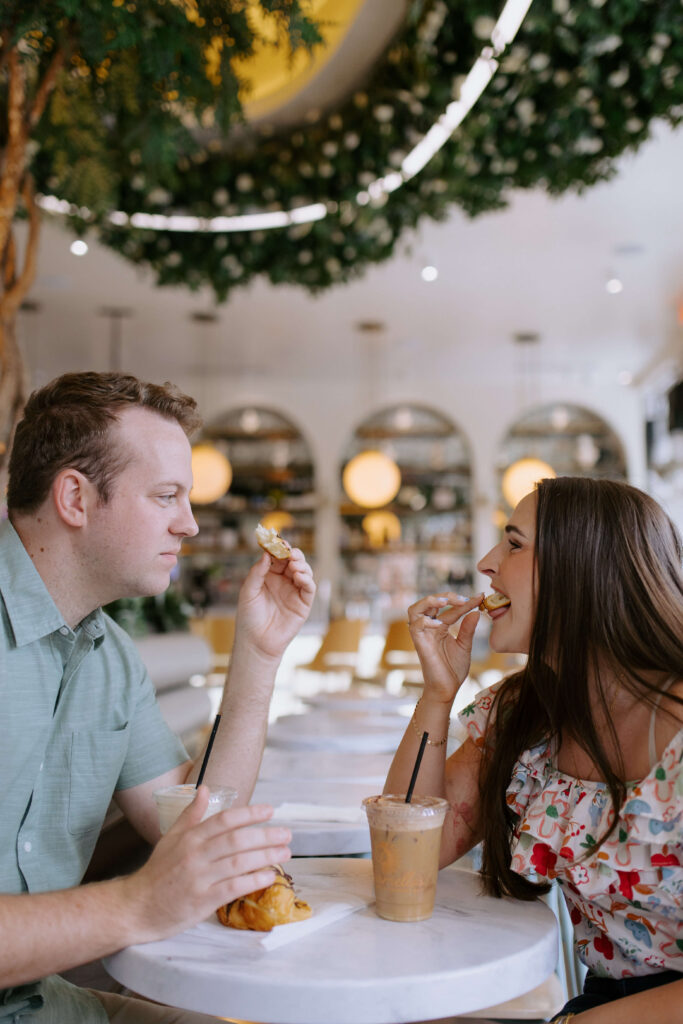 couple in greenville sc at a coffee shop eating pastries looking at each other