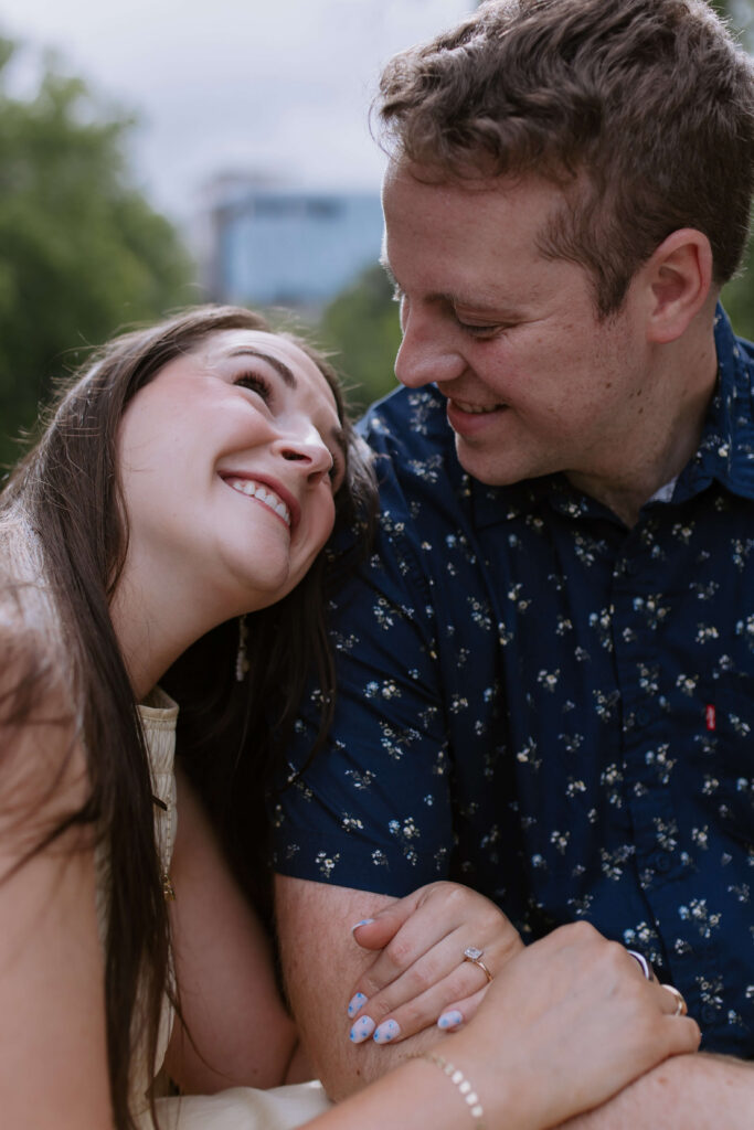 woman hugging man's arm and leaning on his shoulder while he looks at her